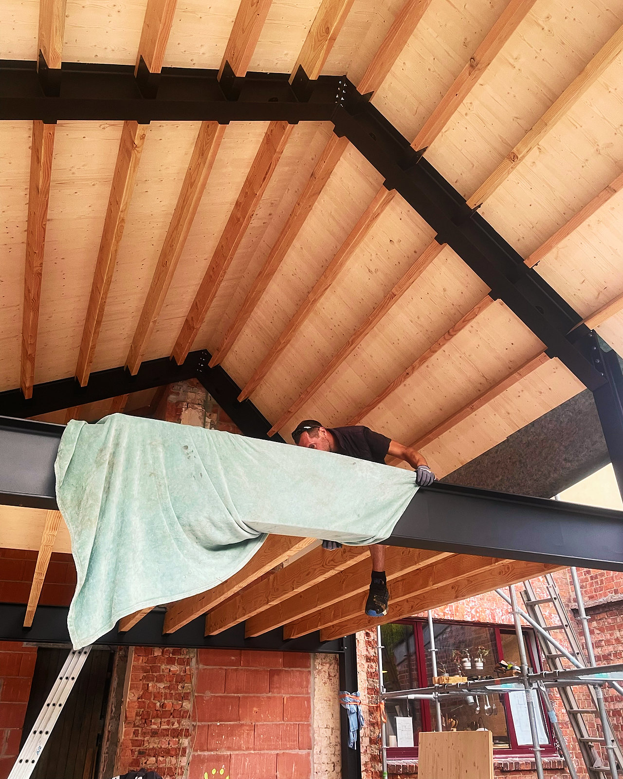 Een stalen balk onder het houten plafond van de nieuwe dakopbouw.