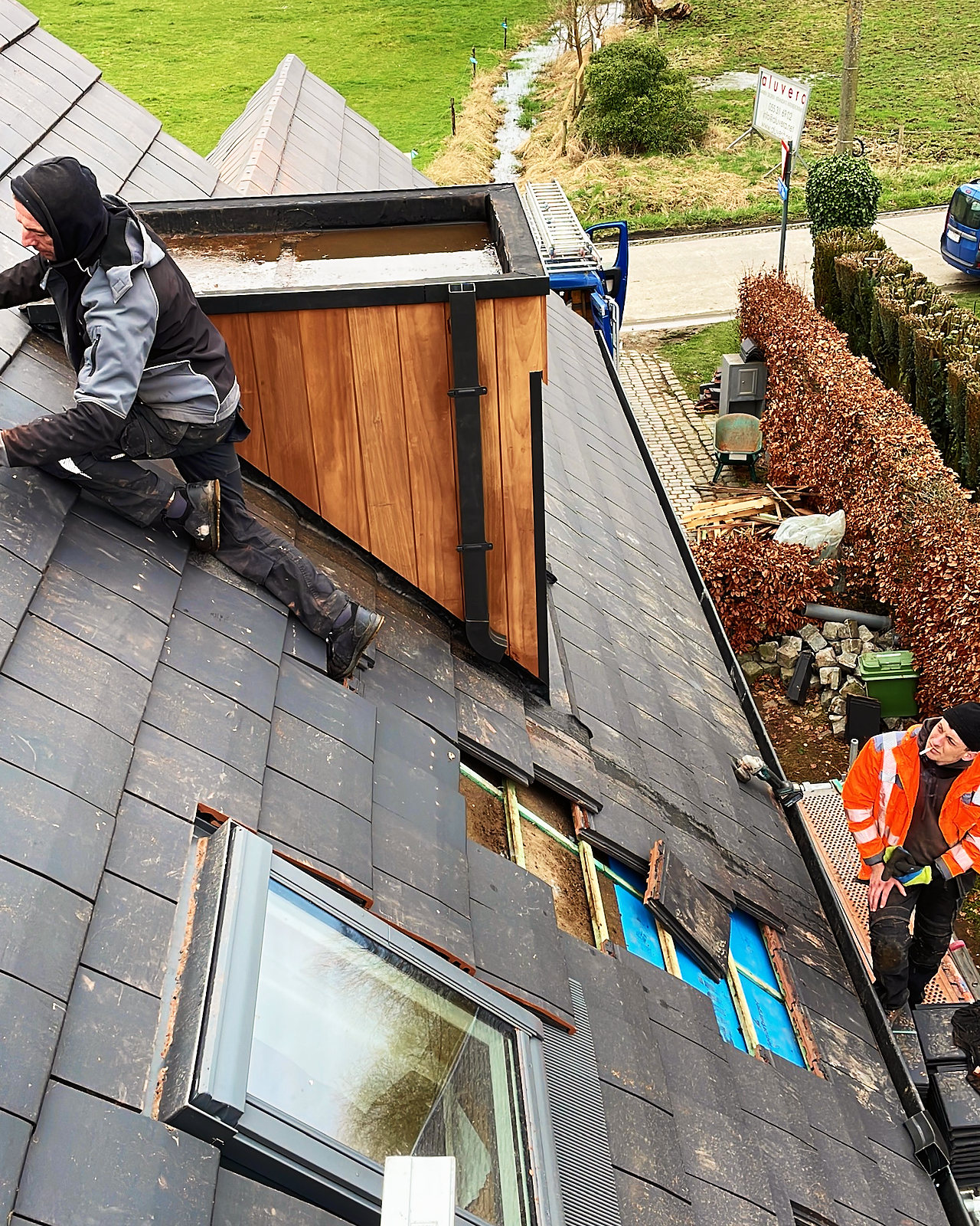 Een dakkapel met houten bekleding in opbouw, gezien van bovenaf op het dak.