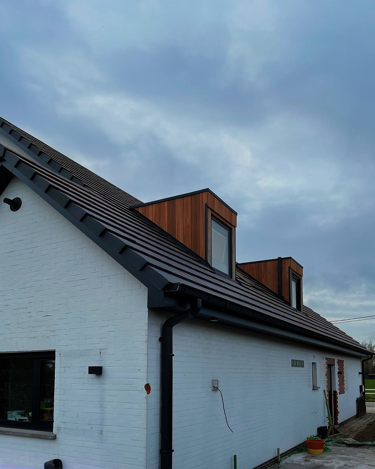 De afgewerkte woning: twee dakvlakken in donkere pannen boven de witte gevel.
