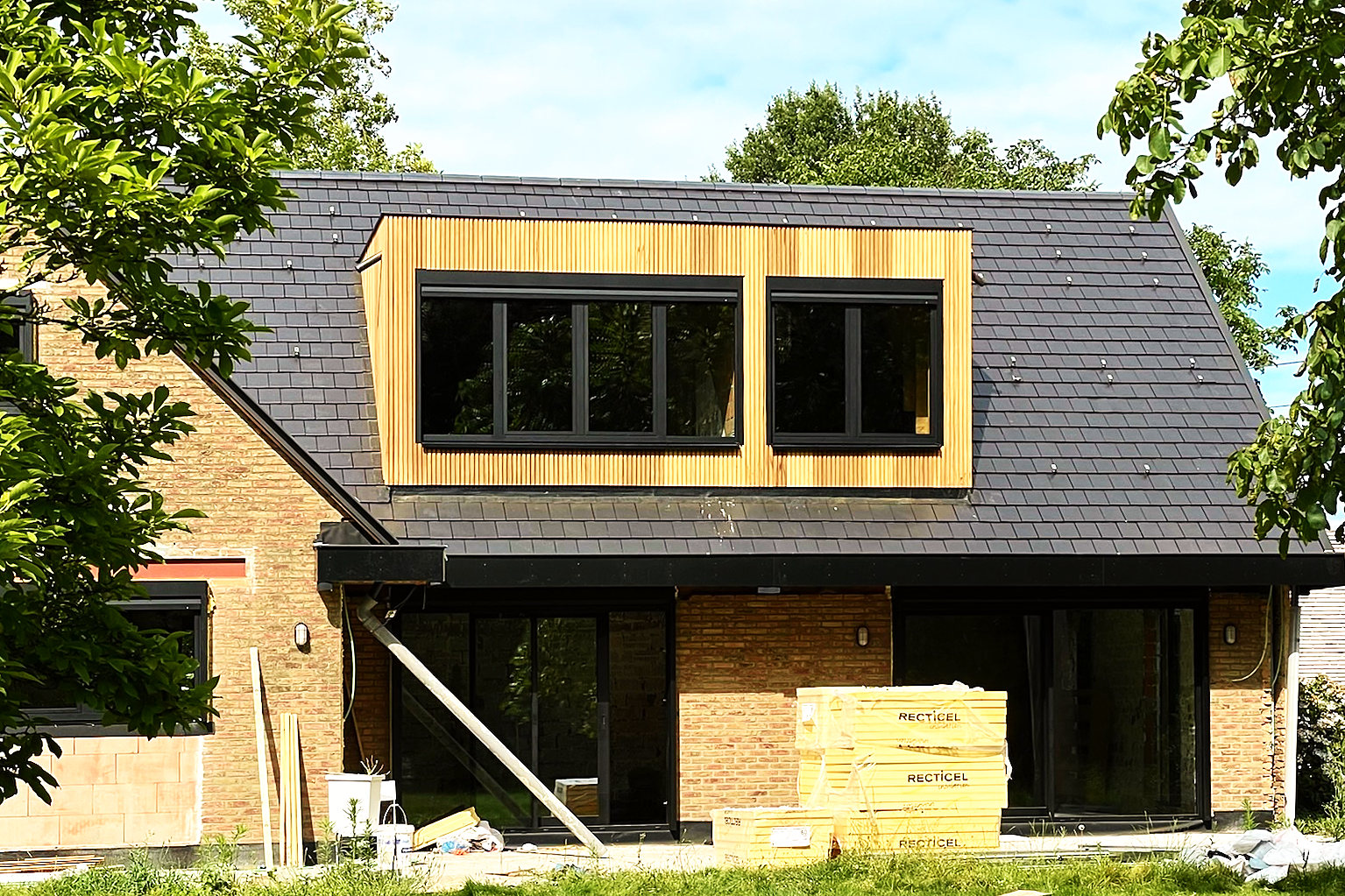 De afgewerkte woning: dak in leizwarte Giverny-pannen met een brede dakkapel in thermowood ayous.
