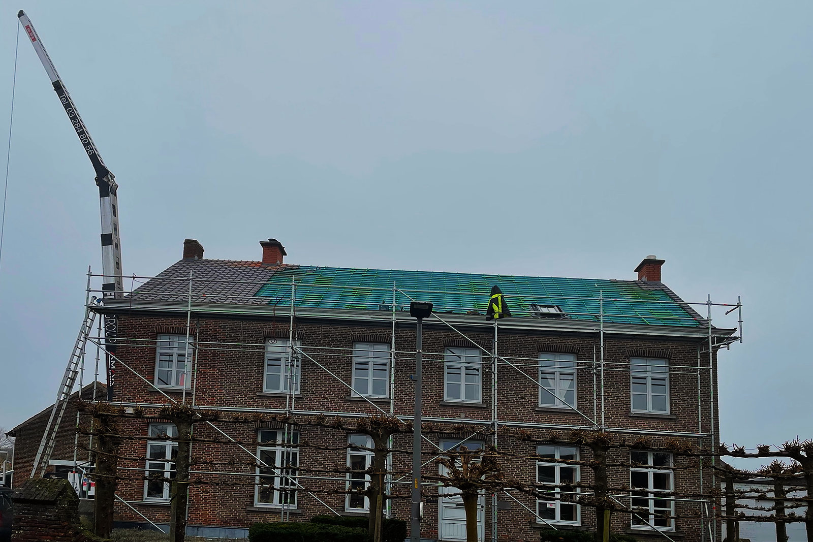 De voorgevel in de stelling terwijl het dak een nieuw onderdak krijgt.