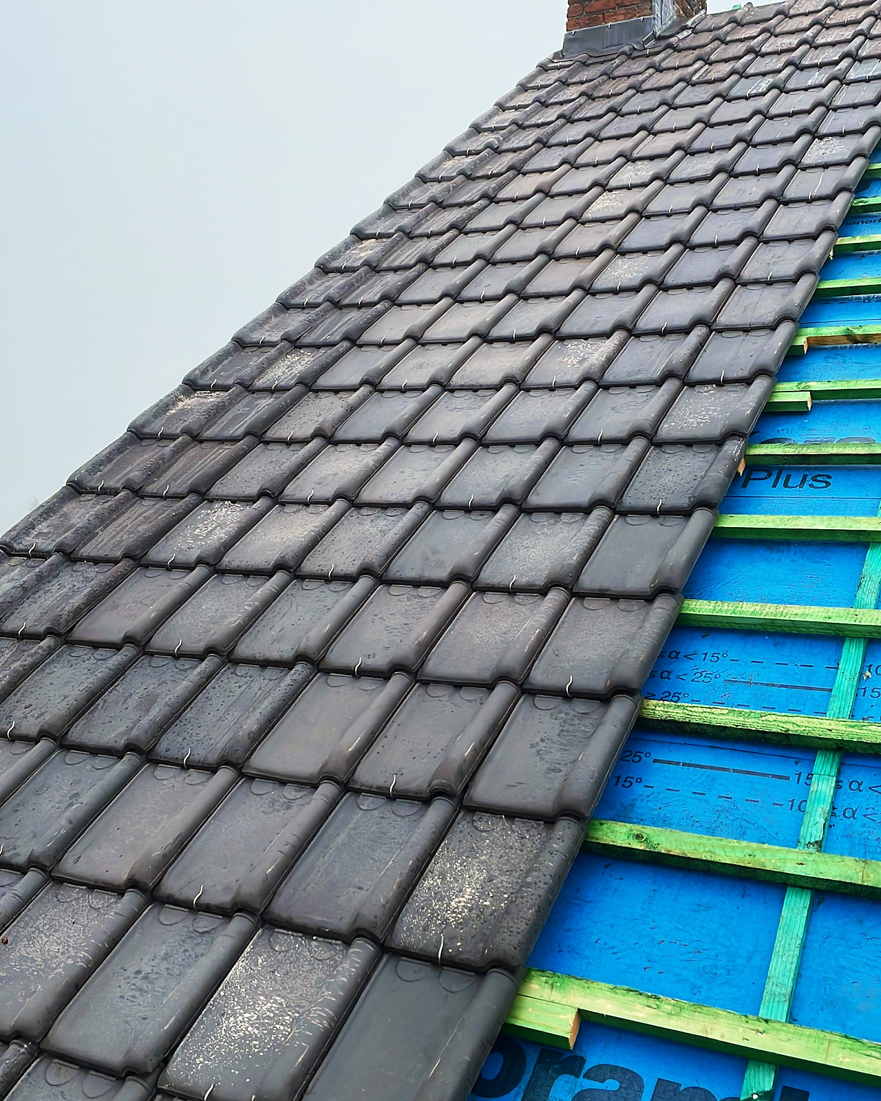 Detail van de nieuwe grijze dakpannen, gelegd op panlatten over het nieuwe onderdak.