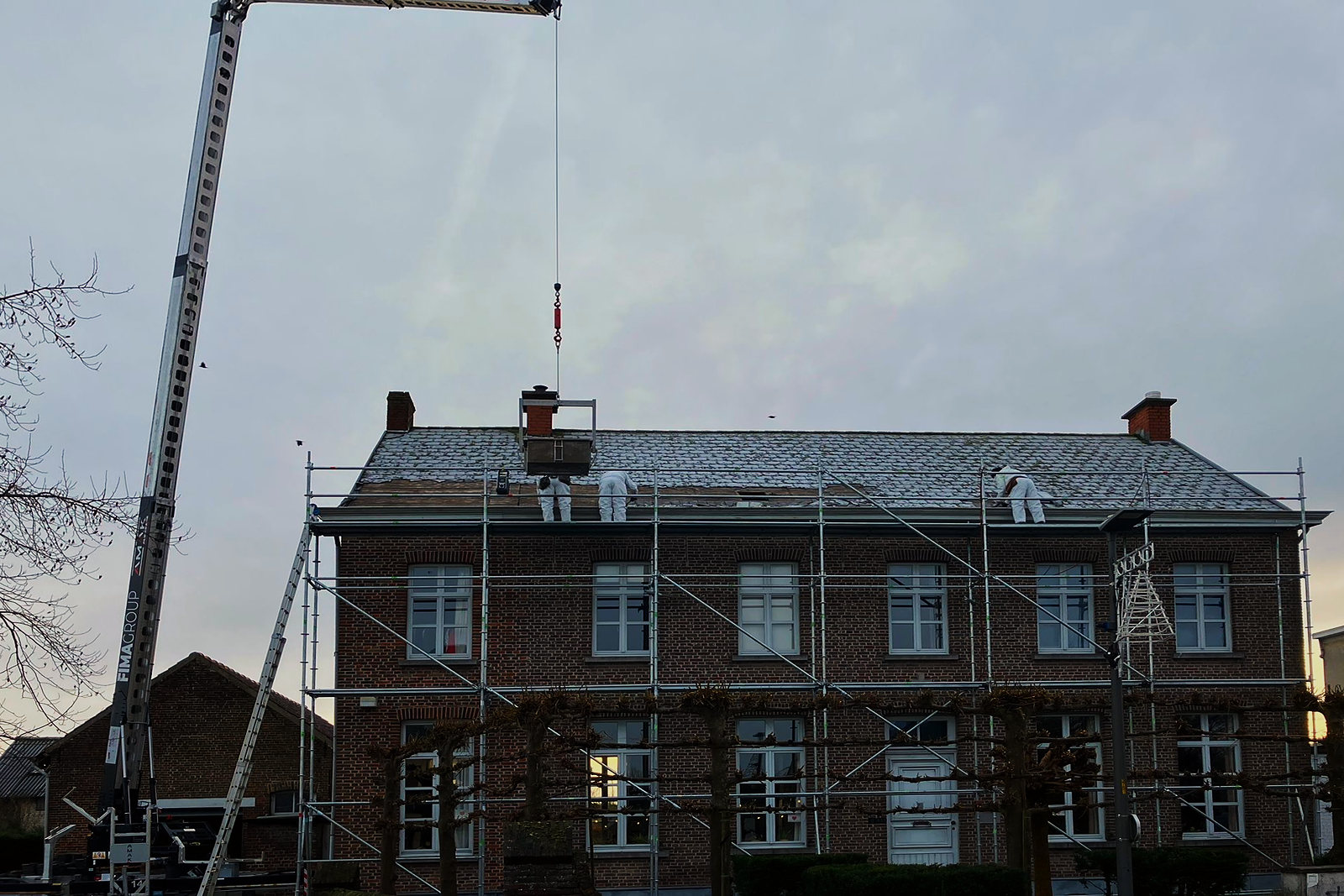 De kraan brengt materiaal naar het dak van het herenhuis.