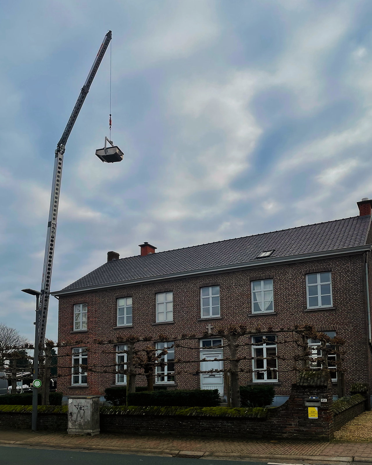 Zicht op het herenhuis van opzij, met de kraan en het nieuwe dak.