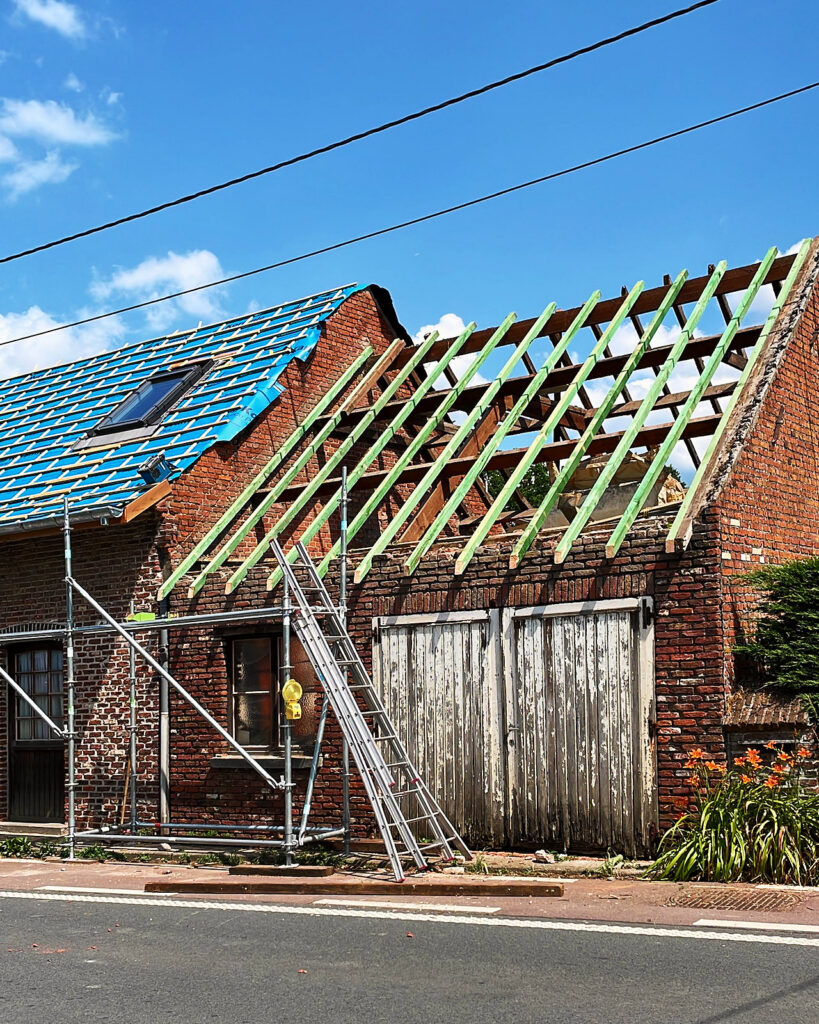 Het dak tot op de houten structuur vrijgemaakt, met de stelling ervoor.