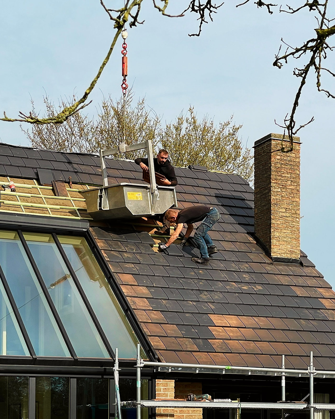 Vakmannen op het dak nemen materiaal aan dat de kraan naar boven brengt.