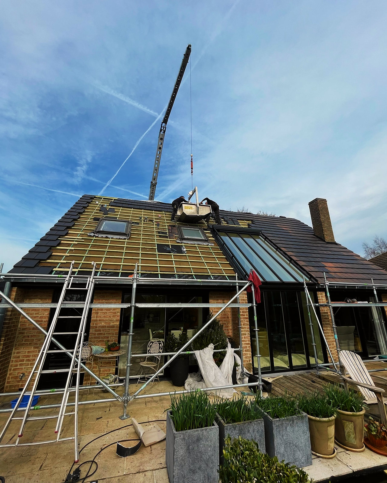 Het dakvlak met nieuwe panlatten, klaar voor de pannen, met de kraan erboven.