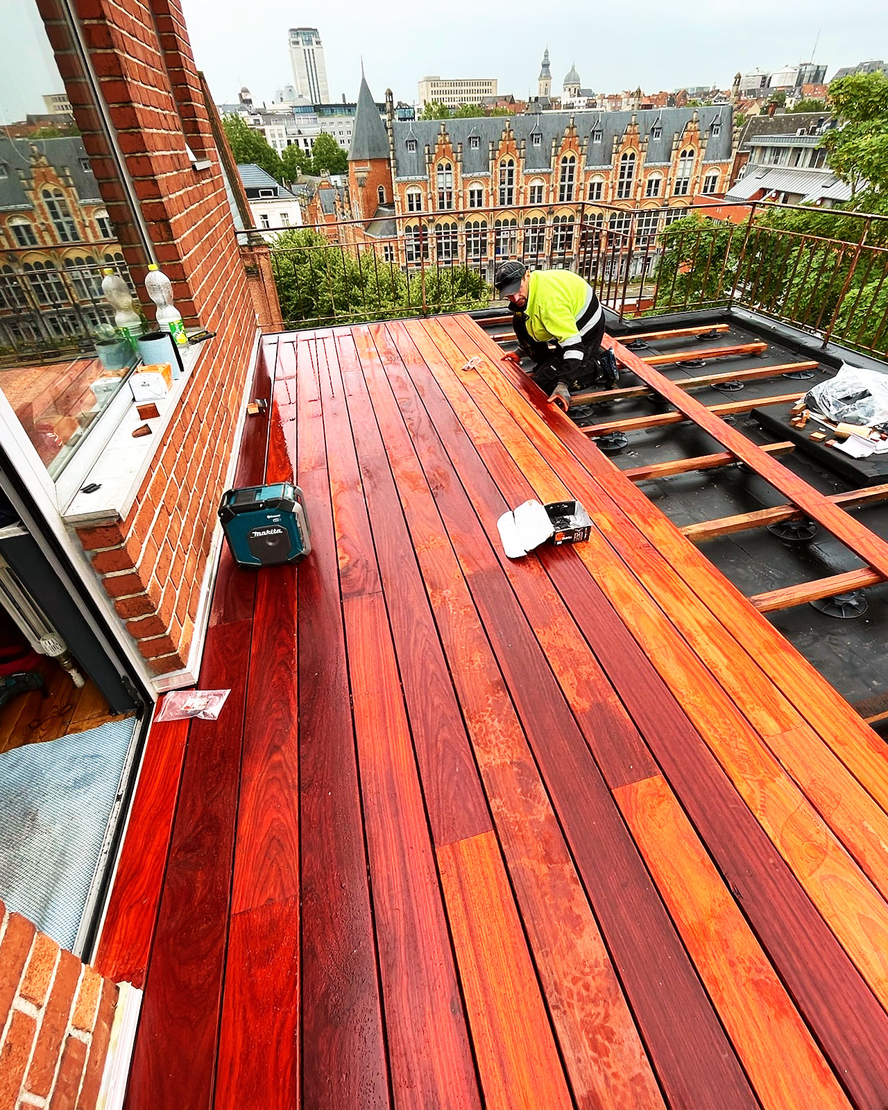 Een vakman van Vlerick Dakwerken legt de planken in padoek op de draagbalken van het terras.