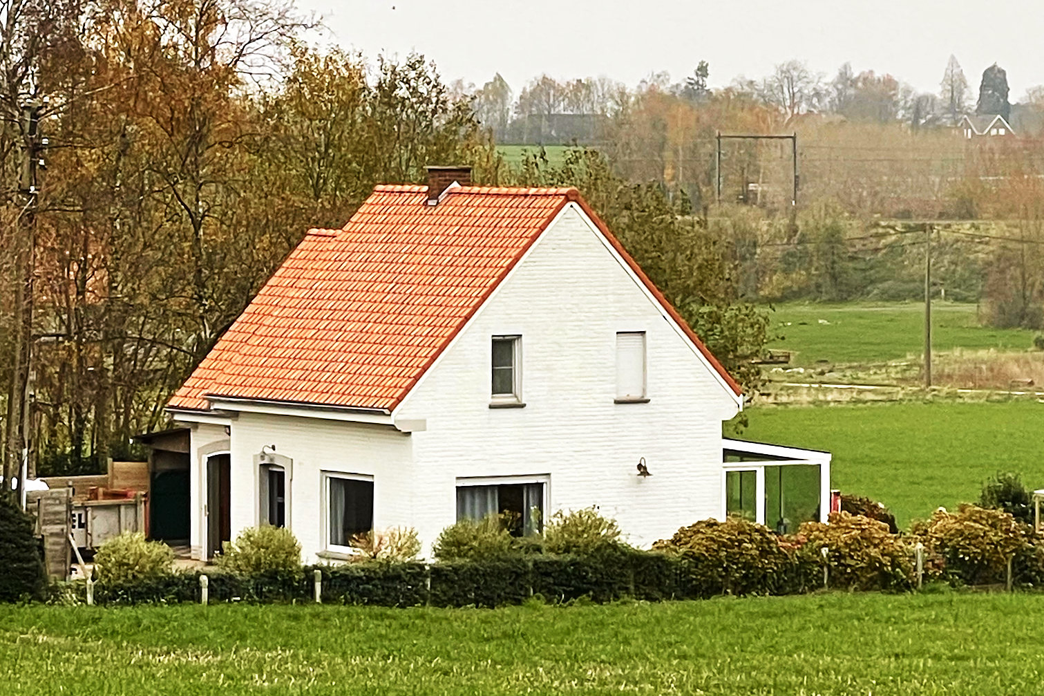Een witte woning in het groen met een volledig nieuw dak in rode pannen.