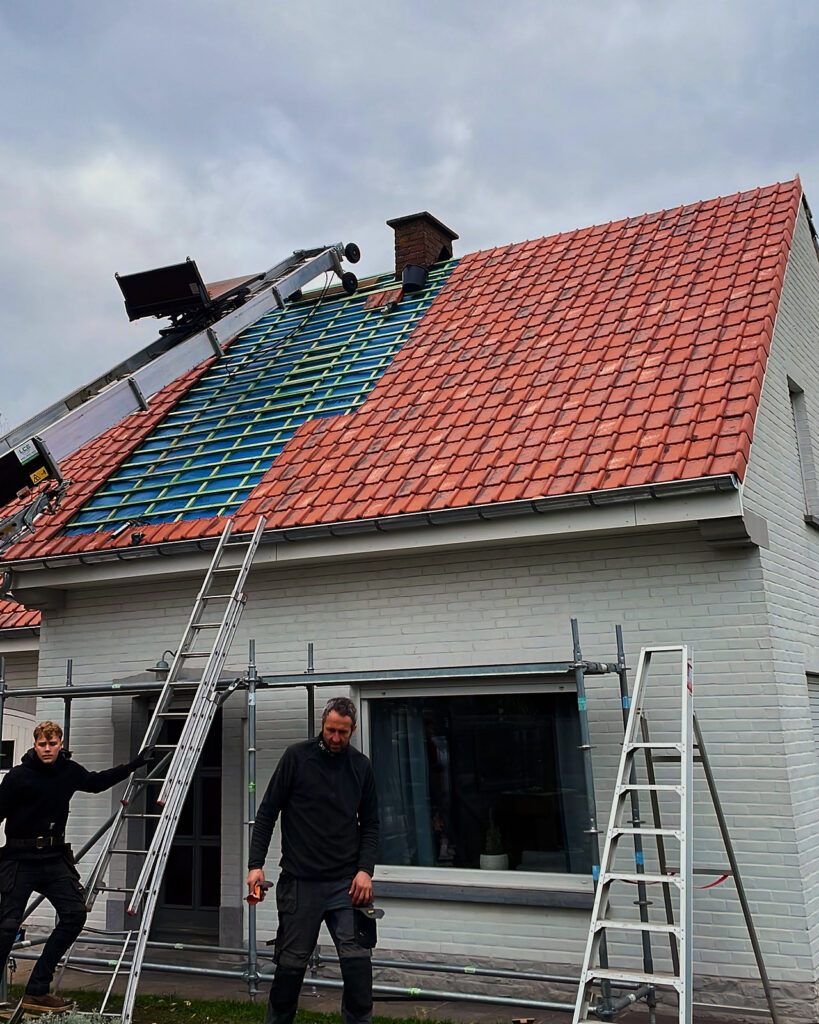 Een dakvlak dat half in nieuwe rode pannen ligt, met de ladderlift ernaast.