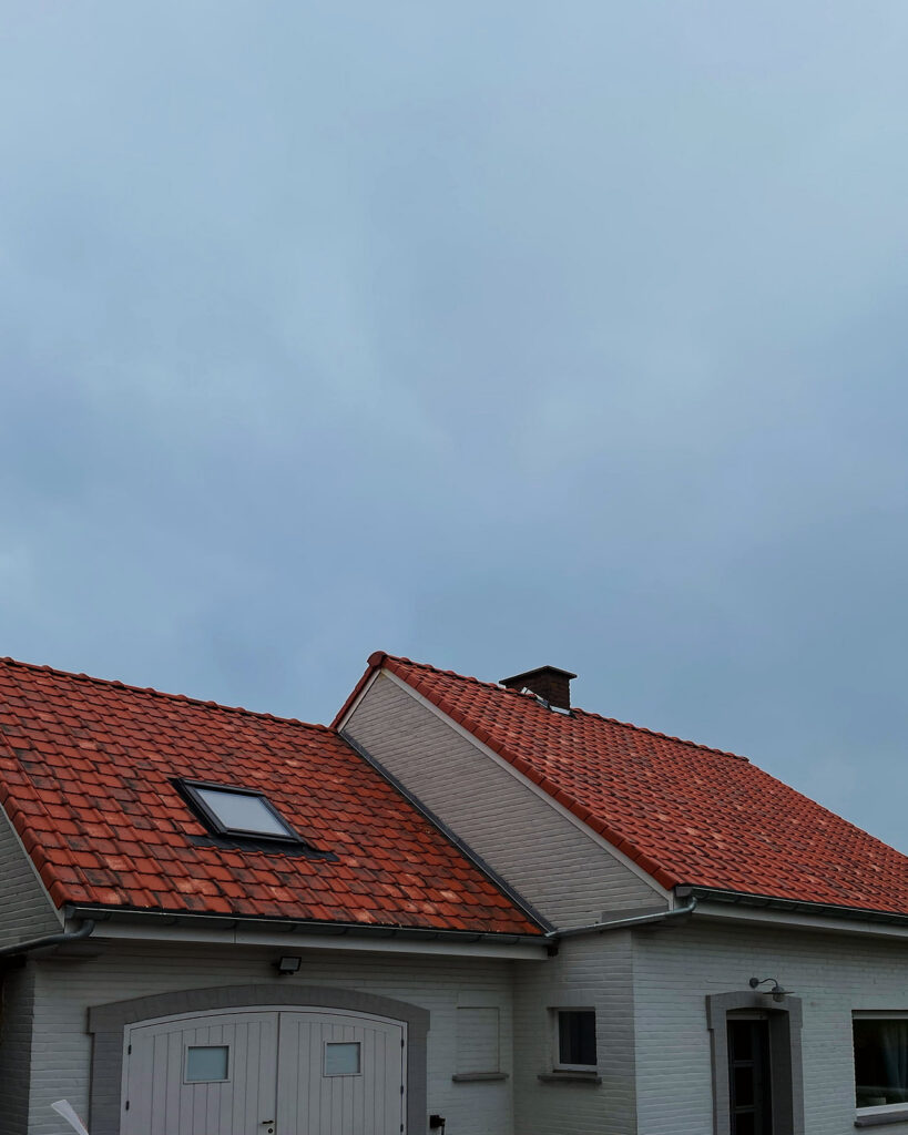De afgewerkte dakvlakken in rode pannen met een dakraam.
