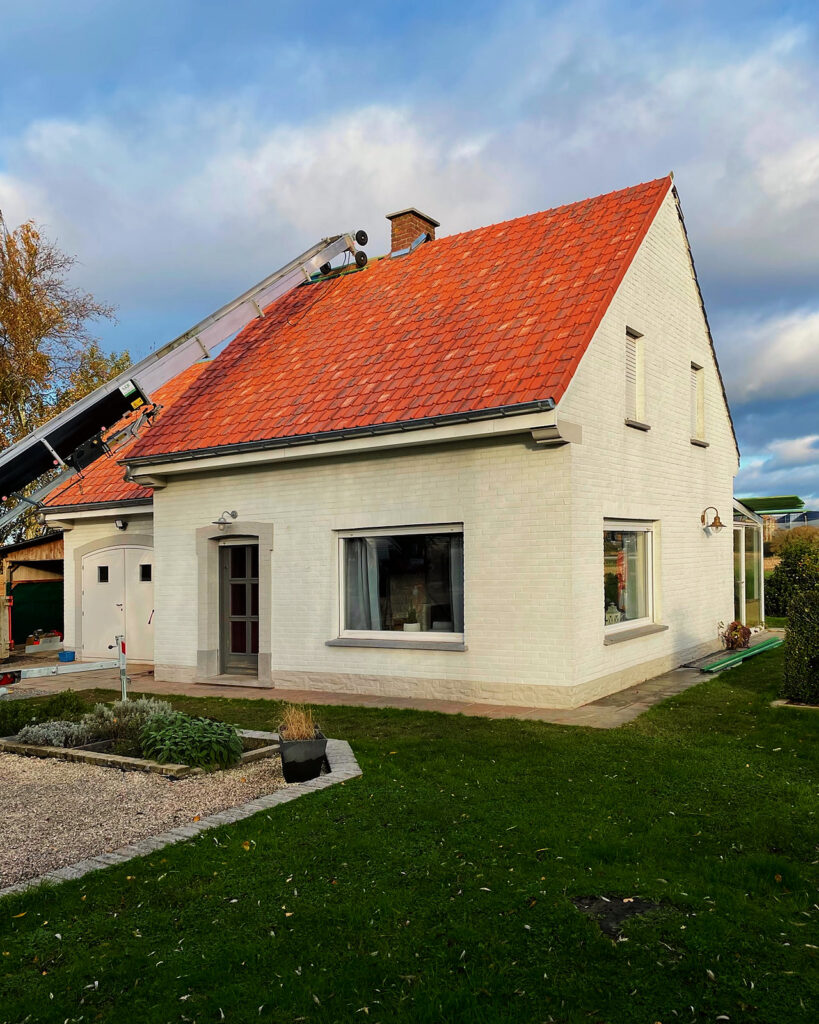 Zicht op de woning met het nieuwe rode dak vanuit de tuin.
