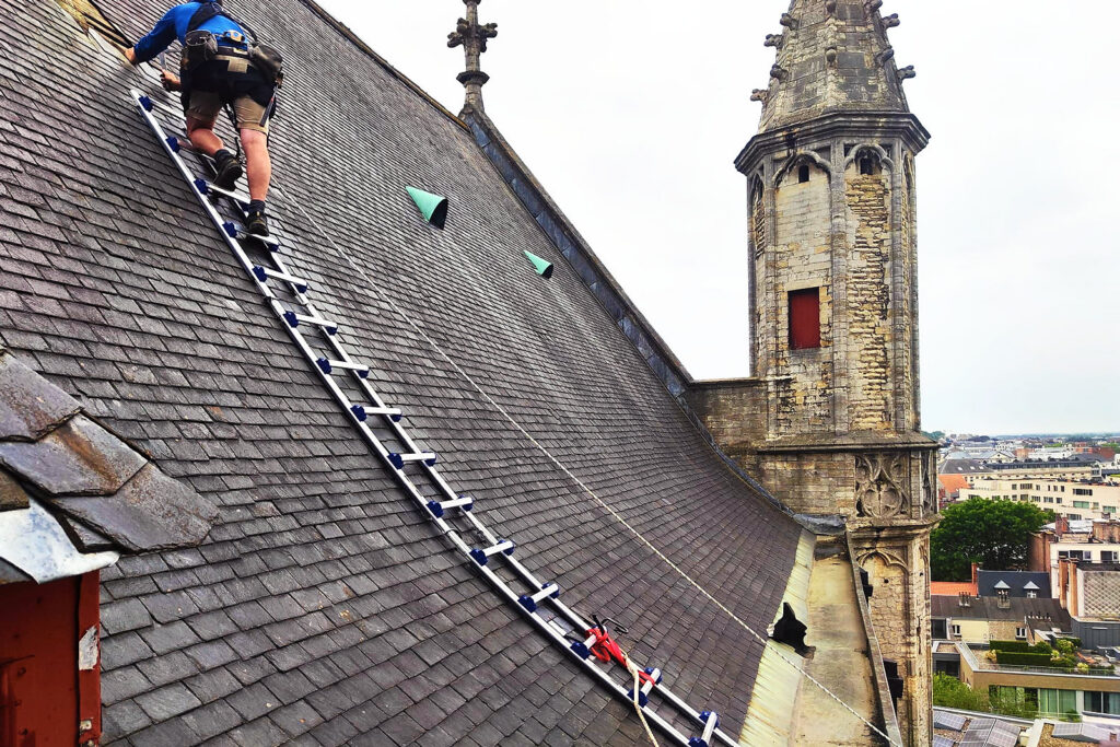Een dakladder over het leiendak van de Sint-Baafskathedraal, naast een gotisch torentje.