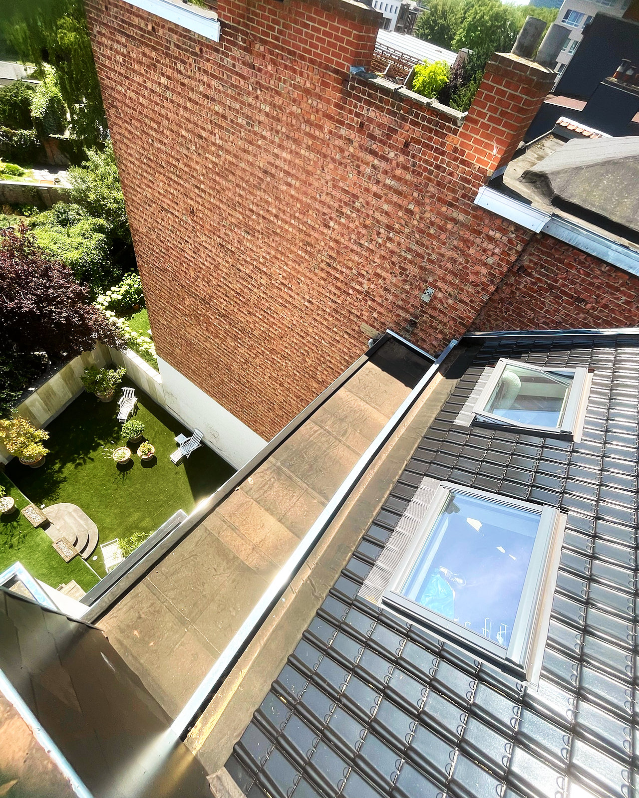 De goot en de dakramen in het nieuwe dak in zwarte pannen.